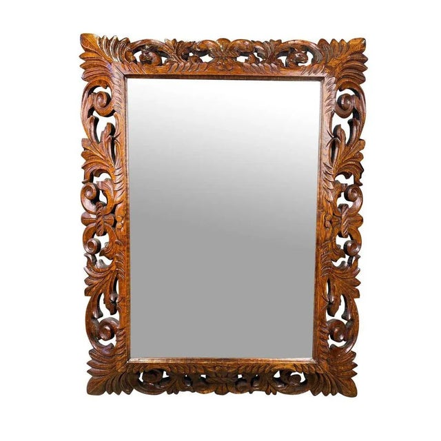 Extravagantly carved mahogany mirror in rectangular dimension. A lovely grain pattern runs symmetrically across the wood...