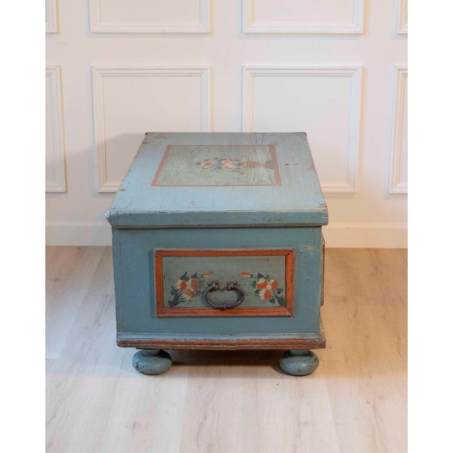 An antique Alpine chest in fir wood, beautifully retaining its original painted finish in a soft, time-worn blue. The...