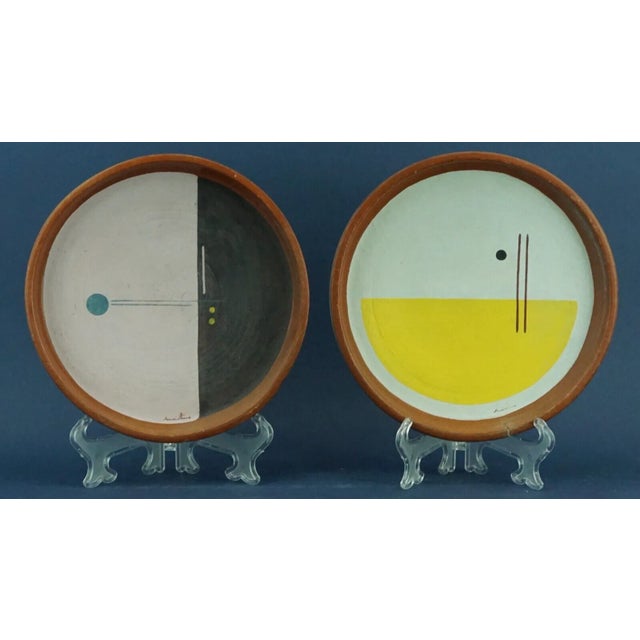 Item : A pair of hand-shaped terracotta plates, crafted on a wheel, with abstract geometric decorations, both signed by...
