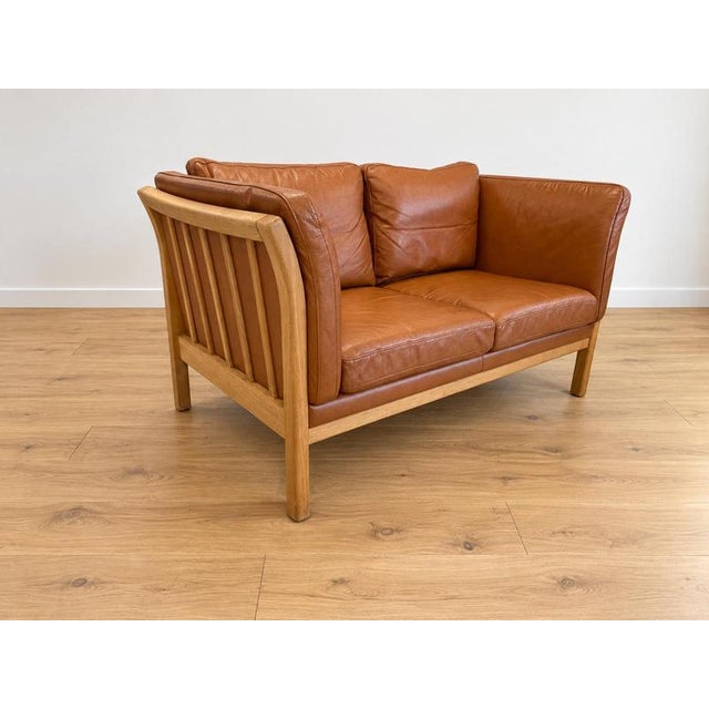 Made in Denmark by , this is a beautiful vintage Danish classic 2 person sofa upholstered in soft cognac leather, the sofa...