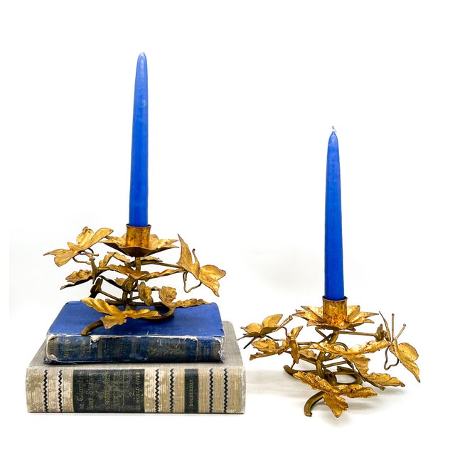 Striking pair of vintage Italian gilt tole candleholders featuring leaves, winding vines, and delicate butterfly accents....