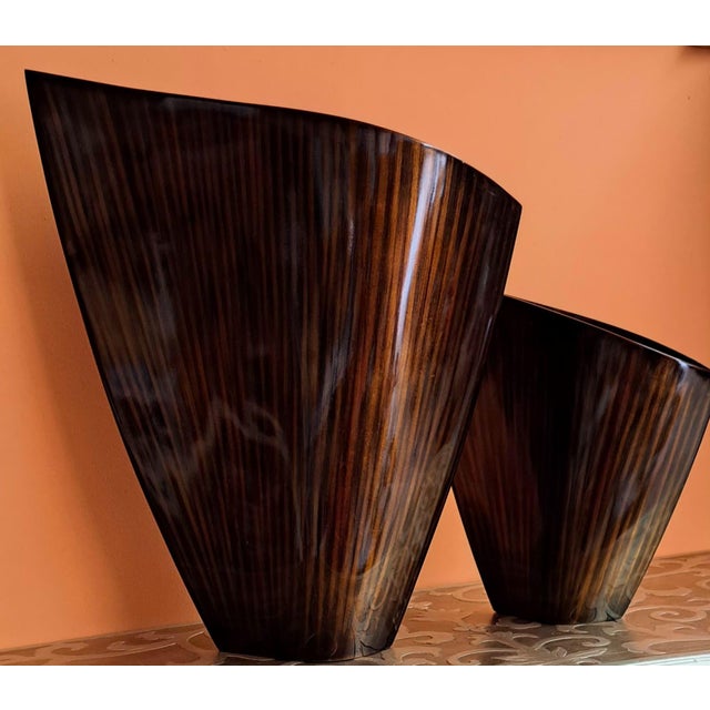 Set of two contemporary, sculptural wooden vases with pronounced grain and a visually fluid finish. They are teardrop-...