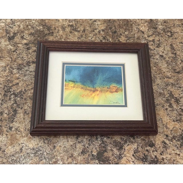 An evocative original abstract watercolor inspired by the meeting of sky, land, and light. Rich teal and deep blue blend...