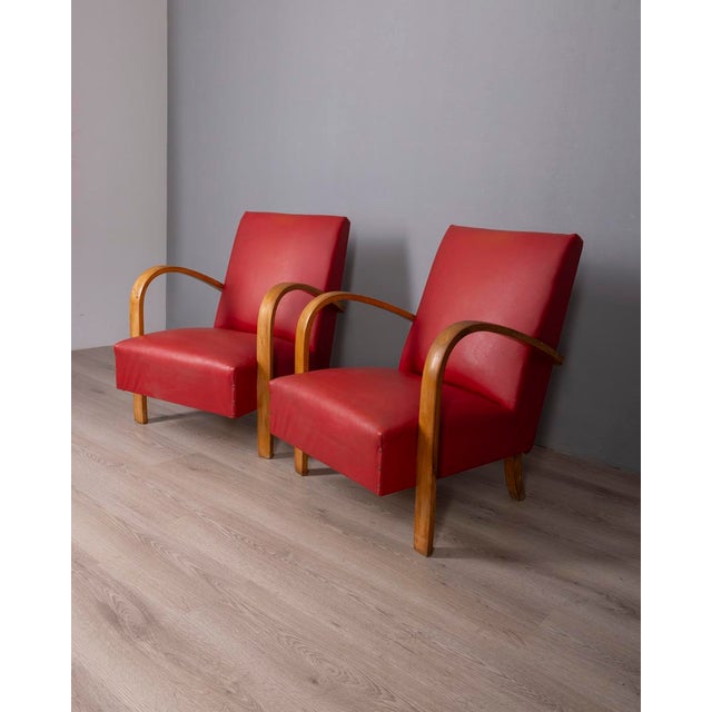 Pair of armchairs with curved wooden frame and red faux leather upholstery, Italian design, 1950s.