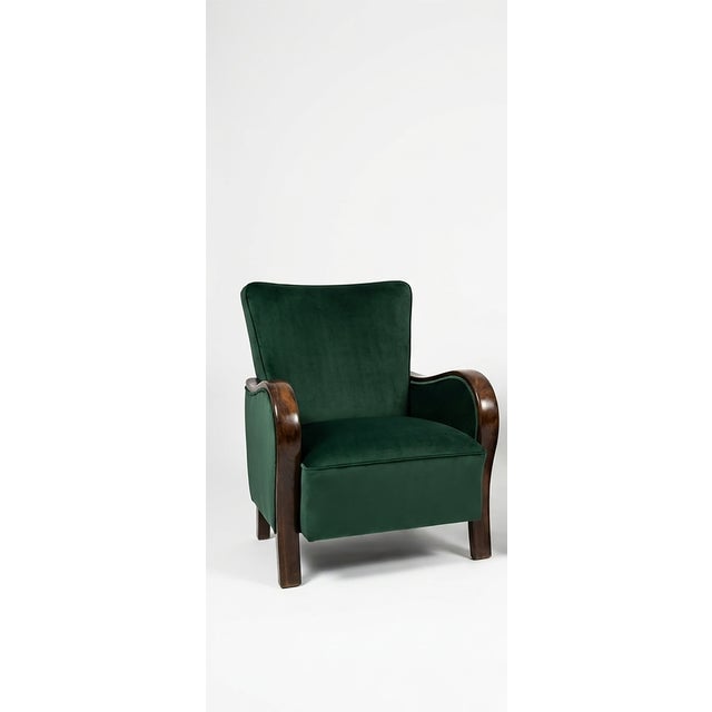 A stunning pair of vintage armchairs featuring a rich, deep emerald green velvet upholstery paired with beautifully...