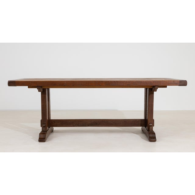 A characterful oak trestle table retaining its original patina, emphasizing authenticity and age. The natural wear...