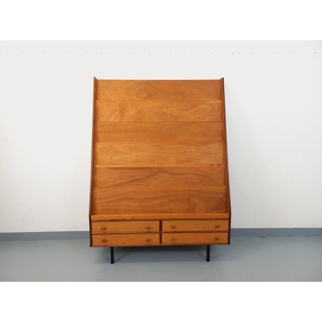 Vintage 1960s bookcase display unit, made of wood with black metal legs, featuring six shelves for books and four drawers...