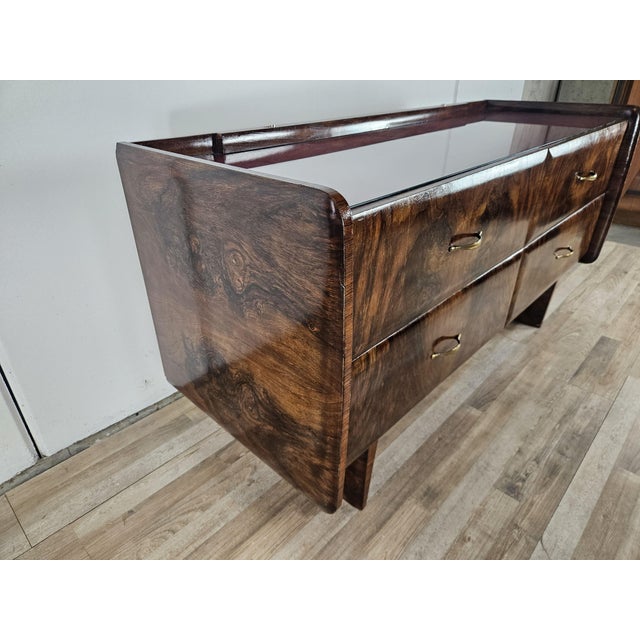 A distinctive 1950s chest of drawers covered in burl wood and featuring four large, roomy drawers. Its sleek design and...