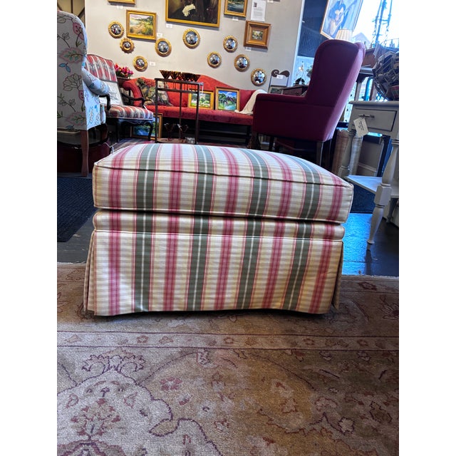 This is a rolling plaid ottoman by Jessica Charles. It is covered in a pinstriped fabric with a fabric skirt covering the...