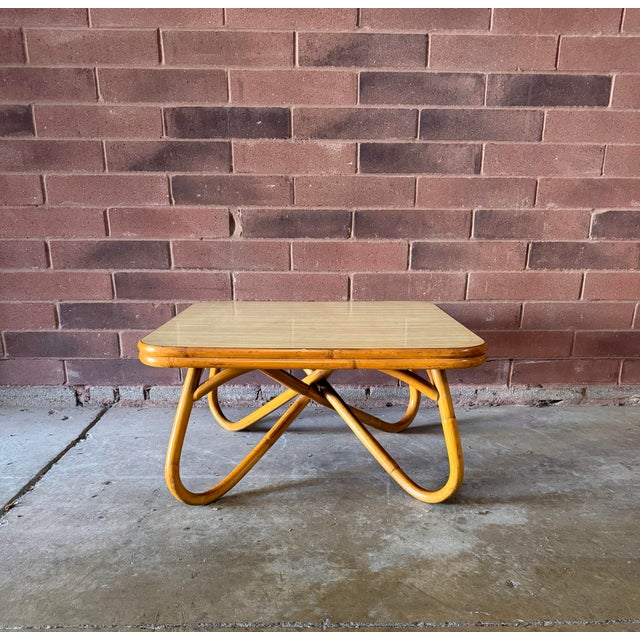 Vintage 1970s rattan coffee table with a sculptural bent-rattan base and softly rounded square top. The warm honey-toned...