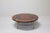 Round coffee or living room table with four brass legs, a wooden top, and brass details. The unique tabletop features a...