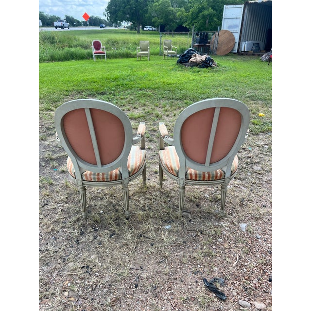 Pair of 19th Century Louis XVI Armchairs crafted with hand-carved and painted wood frames, featuring elegant oval backs,...