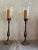 A wow-inducing pair of wood-finished heavy metal candle stands with glass hurricanes, measuring 36.5” tall to the top of...