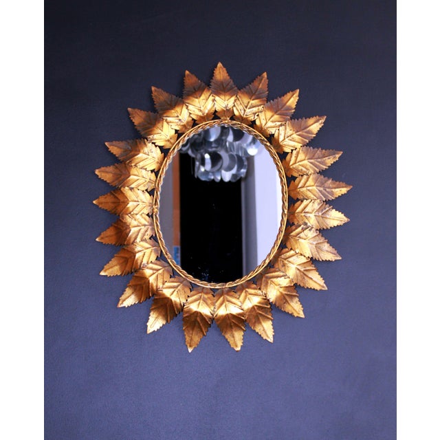 Oval mirror surrounded by a decoration of rope and leaves in gilded and patinated metal with an old bronze complexion. In...