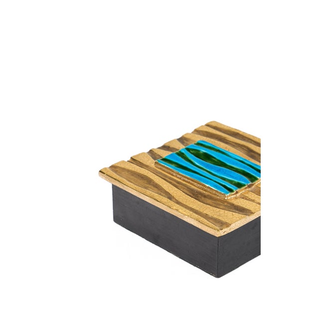 Black-painted wooden box with glazed ceramic top with crackled gold and precious blue stone adornments. The box was is...