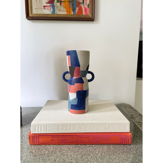 Hand-painted urn style vase with geometric abstract shapes throughout. This vase has unexpected rounded handles at the...