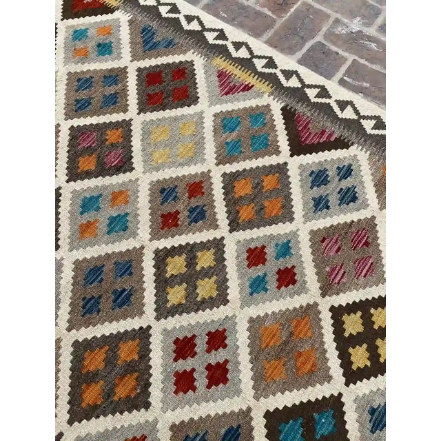 traditional charm into your home with this handwoven Afghan kilim rug. Featuring a vivid geometric design, this rug...