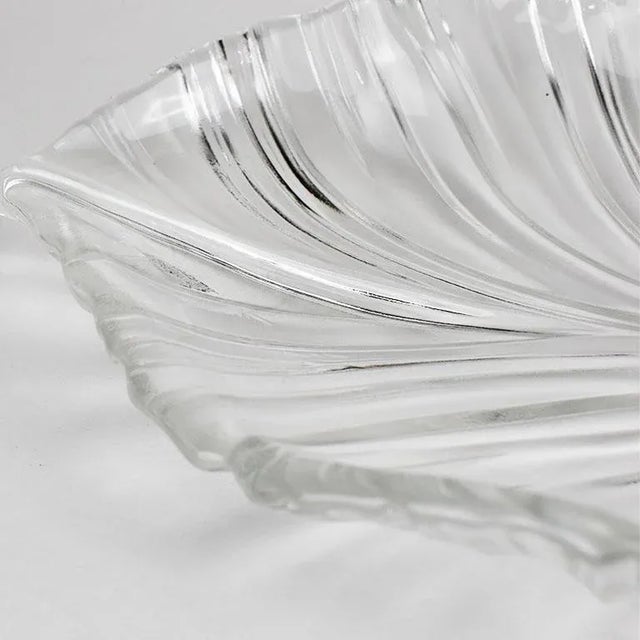 A large glass serving platter in the shape of a palm leaf with a Hibiscus flower at the stem. The top of the platter is...