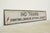 Reclaimed movie set street sign made of plastic foam board in white and black colors. The sign reads "IND TRAINS, DOWNTOWN...