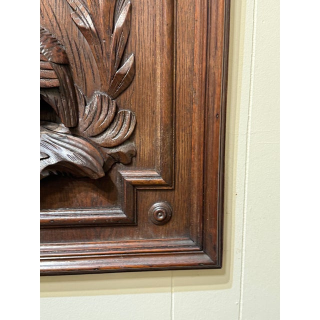Hand-carved solid wood wall panel depicting a bird motif framed by an architectural border. The carving shows expressive...