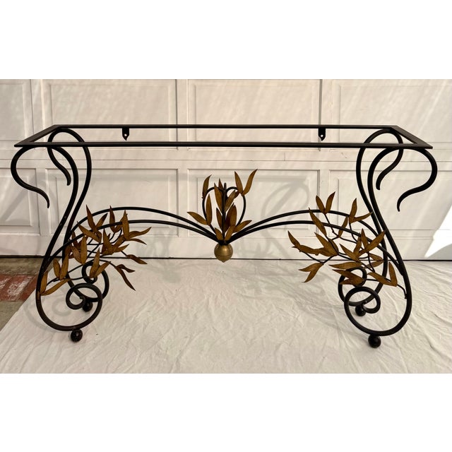 Here is a stunning mid-century Hollywood Regency iron and glass console table, dating to the 1950s–1960s, featuring...