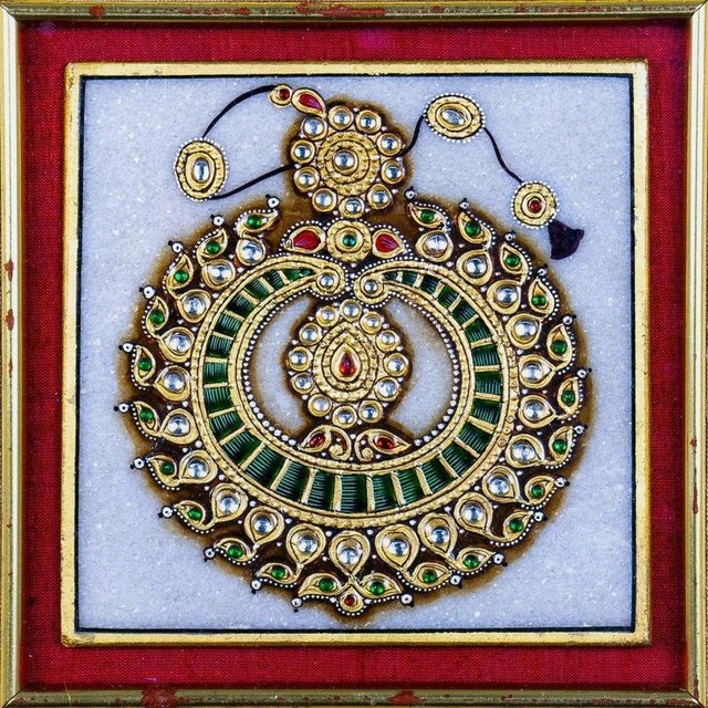 A striking Indian decorative plaque featuring an elaborate jewel-like circular ornament, finely arranged with green, red...
