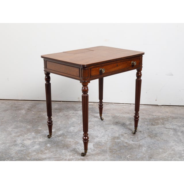 An English mahogany table from the 19th century, with single drawer, small compartment and reeded legs. Created in England...