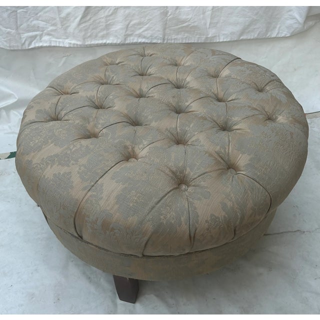 This lovely Lovely round ottoman or footstool has a tufted top and is upholstered in a Damask with light gold and silver...