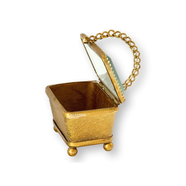 Late 19th century English gilt jewelry box with ornate textured decoration, ball feet, and a delicate chain-form handle....