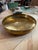 A striking vintage hand-hammered brass centerpiece bowl from the 1970s, featuring a broad circular form with a gently...