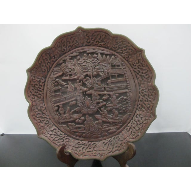 Antique Chinese cinnabar lacquer style plate pair with stands. Dark reddish brown resin showing intricate, court or...
