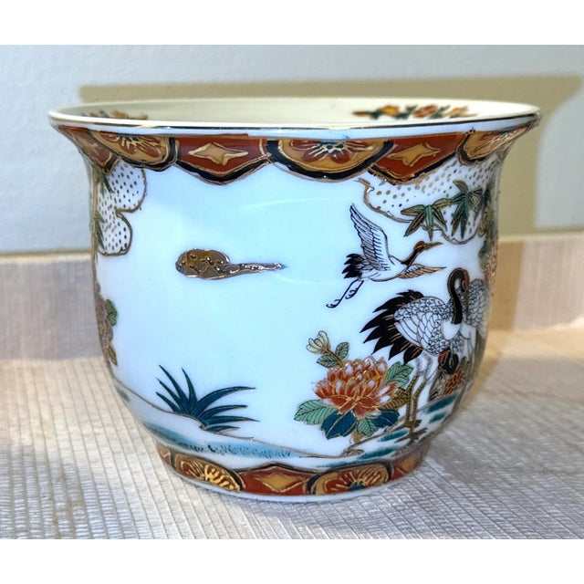 A pair of vintage chinoiserie planters featuring a striking design of black and gold cranes. These exquisite cachepots are...