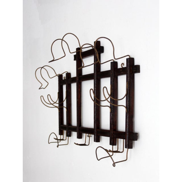 This antique turn-of-the-century wall hat and coat rack pairs a dark-stained wood frame with sculptural bent-wire hooks,...