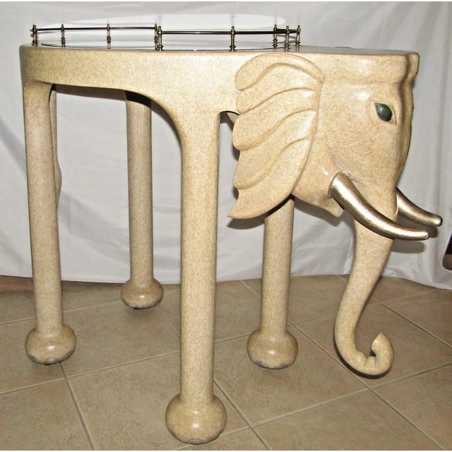 The Hand Carved Wood Elephant Rolling Bar Cart Table by Marge Carson, circa 1990s, is a unique and stylish piece of...