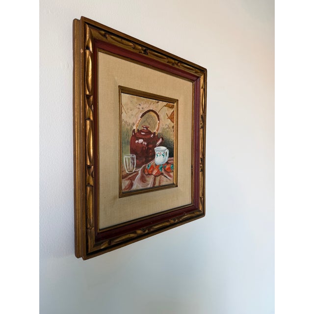 Charming 1970s still life oil on board painting depicting a rustic tabletop arrangement featuring a glazed teapot, hand-...