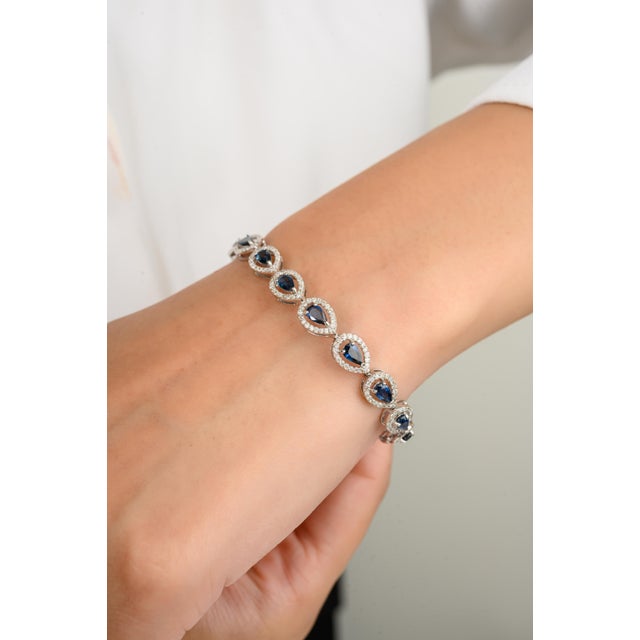 This stunning tennis bracelet features pear-cut sapphires, each surrounded by a radiant halo of diamonds. The elegant...