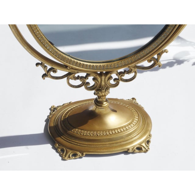 Vintage brass oval shaped vanity mirror. The mirror can be turned due to its mechanism and has a beautiful ornate frame....