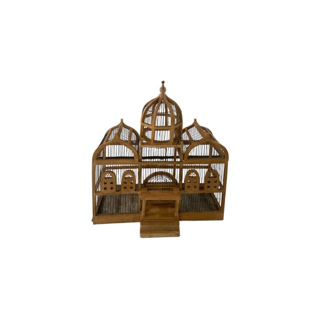 This vintage architectural bird cage has a pair of peaked roofs and tall center dome under which is a pediment portico...