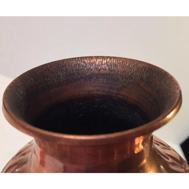 This embossed copper vase depicts a group of men holding weapons and religious artifacts. The piece was made by hand by an...