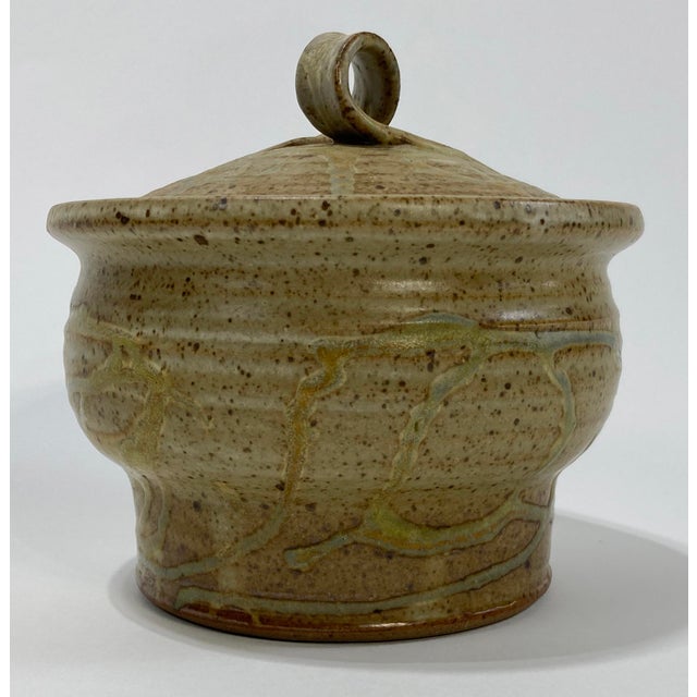 Vintage lidded studio pottery bowl with variation of brown and soft blue green tones. Unique handle to lid. Marked by...