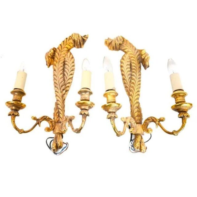 A set of four vintage gilt Prince of Wales plume style wall sconces. Each sconce has two detailed brass curved arms. Two...