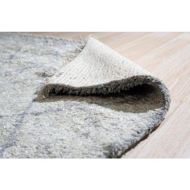 This gray wool rug is a hand knotted pile area rug produced in India. It features a medium pile thickness that provides a...