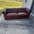 Vintage button tufted brown leather chesterfield sofa with two loose seat cushions. Turned wood bun feet. Rolled arms with...