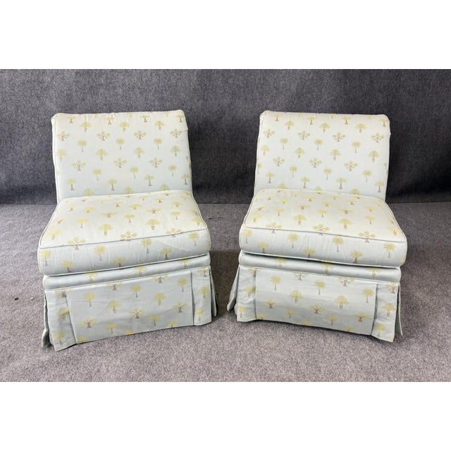 This pair of Calico Corners slipper chairs features an elegant rolled back design with button detailing, upholstered in a...