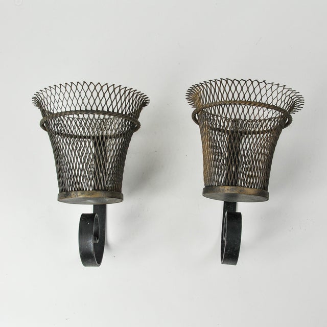 An incredible pair of small antique French wall mounted planter baskets supported by a swirled iron bracket. These unique...