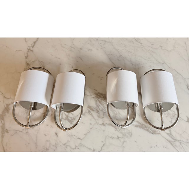 Elegant pair of Bit Wall sconces by The Urban Electric Co., finished in polished nickel and paired with crisp white linen...