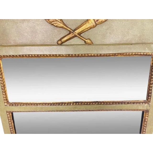 A green painted continental eglomise wall mirror with black column supports and gilded hoof feet. Decorated at the top...