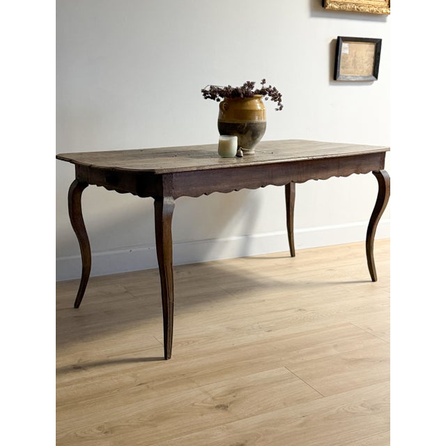 A beautifully proportioned 18th-century French dining table with graceful cabriole legs and a hand-scalloped apron. The...