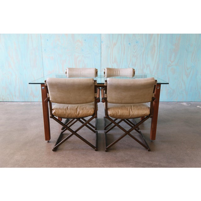 A vintage dining set consisting of a glass top dining table supported by brass stretchers and oak legs and a set of 4...