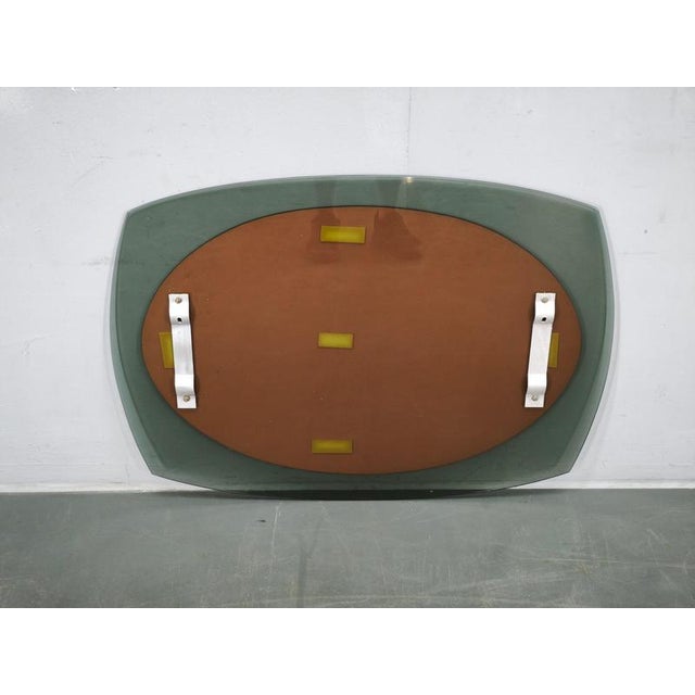 A striking italian modernist wall mirror from the 1970s, composed of a dark smoked-glass outer panel surrounding a large...